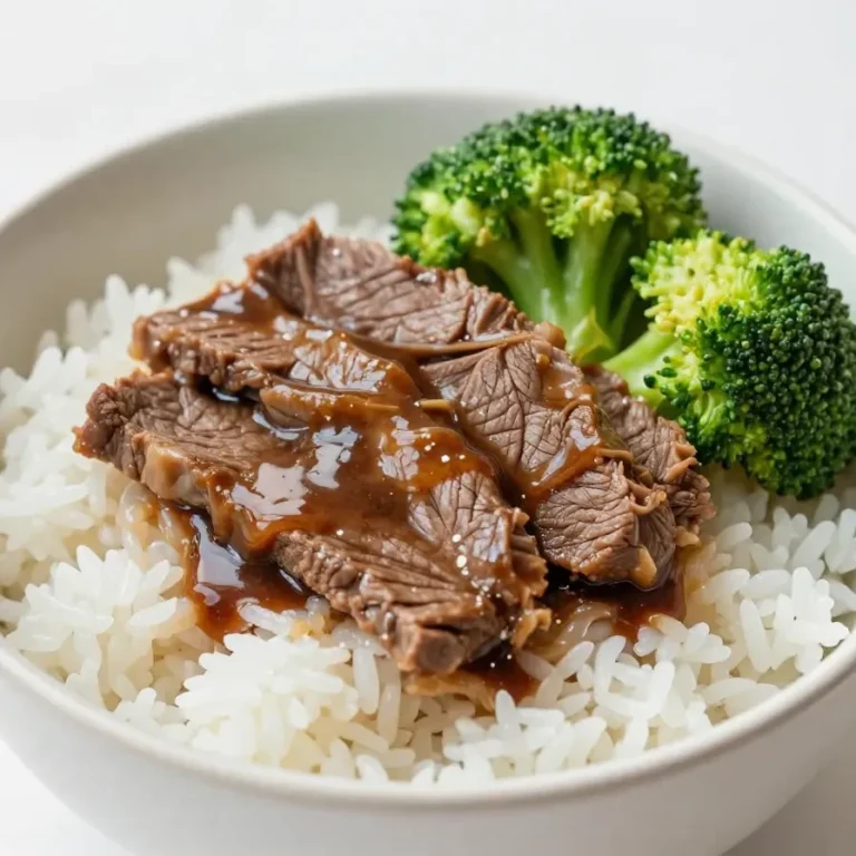 Close-up of a plate of Chinese beef and broccoli served with steamed rice.